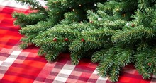 A Close-up Red And Green Checked Tablecloth With A Small Fir Tree Placed On Top Of It. 