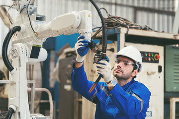 male engineer worker repair automatic robotic arm in factory. male technician worker inspecting qual