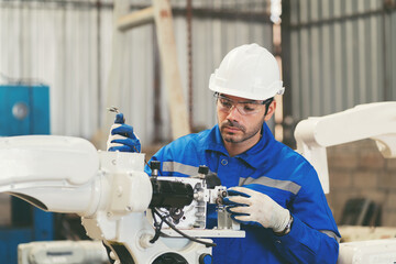 Wall Mural - Male engineer worker repair automatic robotic arm in factory. Male technician worker inspecting quality automatic welding robot arm machine at production line