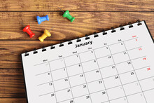 Colorful Push Pins Scattered Near A Monthly Desktop Calendar On A Wooden Table. Illustration Of The Concept Of Time Management, 
Office Schedule And Meetings