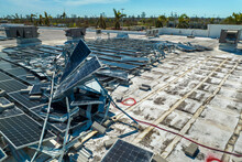 Broken Down Photovoltaic Solar Panels Destroyed By Hurricane Ian Winds Mounted On Industrial Building Roof For Producing Green Ecological Electricity. Consequences Of Natural Disaster