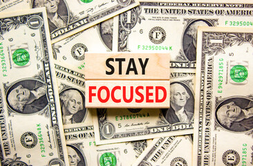 Stay focused symbol. Concept words Stay focused on wooden blocks on a beautiful background from dollar bills. Business, support, motivation, psychological and stay focused concept. Copy space.