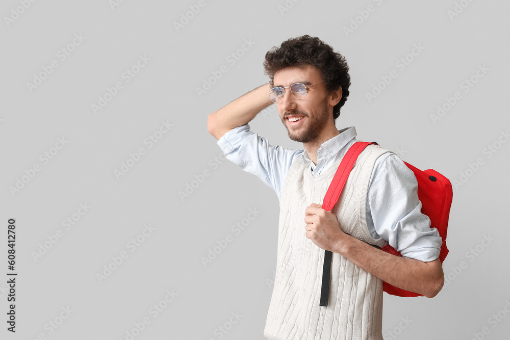 Male student with backpack on light background