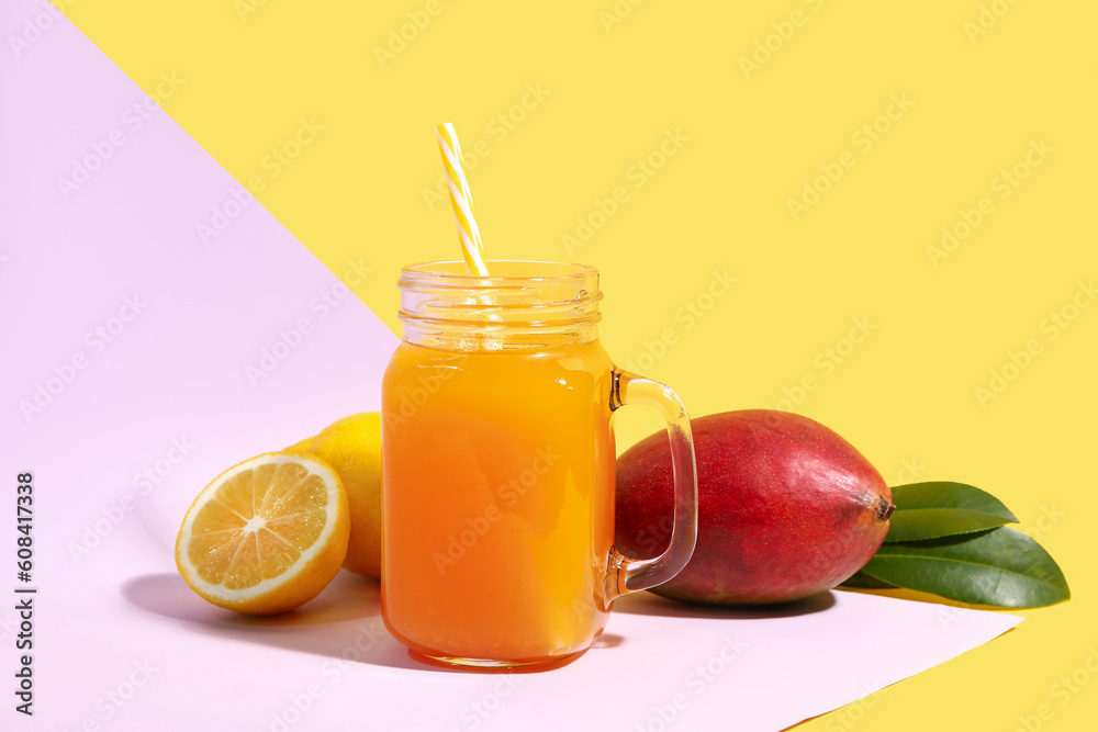 Mason jar of fresh mango smoothie and lemon on color background
