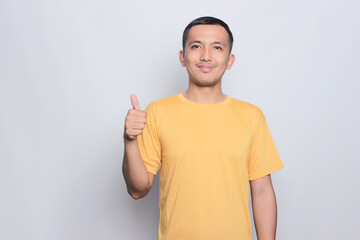 portrait asian young man wearing yellow tshirt with thumb up sign.