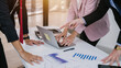 © tong2530 - Close-up hand of Profession businesspeople office workers working in team conference on a laptop with project planning document on meeting table.