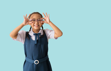 Portrait Happy smile asian school girl in uniform with backpack and hands holding glasses, isolated on pastel plain light blue background