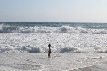  boy on the beach running on the waves of the sea