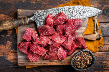 Canvas Print - Sliced Raw venison dear meat for a stew, game meat on butcher cutting board. Wooden background. Top view