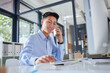© Ruan R/peopleimages.com - Business man, phone call and computer work of a Asian employee with communication at desk. Mobile, conversation and networking for digital sales and online strategy at a office for startup of worker