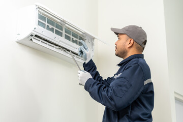 Wall Mural - Technician in uniform using tablet to check list of maintenance and cleaning filters of air conditioner. Air condition maintenance service. Home services concept.