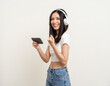 © Chanakon - Beautiful young asian women play mobile game and put on wireless headphone standing on isolated background. Playing game on smartphone winning victory moment. Very enjoy and fun relax time