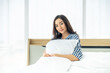 © TeTe Song - Portrait of happiness cute woman sitting on white bed and hugging soft pillow. Conceptual of woman rest and relax lifestyle.