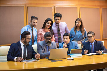 Wall Mural - Indian businessman showing some detail in laptop to his partner and employee at office.