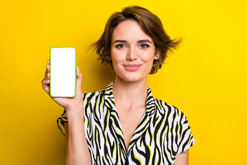 Portrait of adorable lovely lady wear trendy clothes showing empty space modern device display isolated on yellow color background