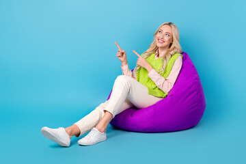 Wall Mural - Full body photo of young business lady lying bean bag relaxing point fingers empty space event zone isolated on blue color background