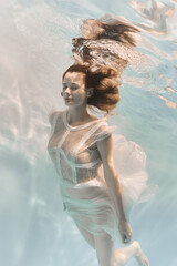 Wall Mural - Portrait of a woman underwater in a lacy white dress in light colors