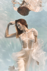 Wall Mural - Portrait of a woman underwater in a lacy white dress in light colors