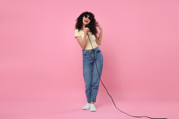 Sticker - Beautiful young woman with microphone and sunglasses singing on pink background