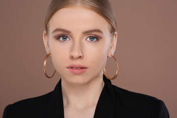 Wall Mural - Beautiful young woman with elegant earrings on light brown background