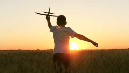 boy teenager child kid runs through field with wheat with toy plane his hands sunset, happy dream family, become pilot, kid wheat plays with toy field, sunset park, spring break, little pilot runs