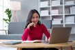 © amnaj - Beautiful young Asian woman sitting using a laptop and take note at home. Young Asian woman student sitting on floor working with laptop computer and taking notes at home.