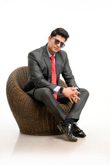 Young and confident indian businessman sitting on chair and giving expression.