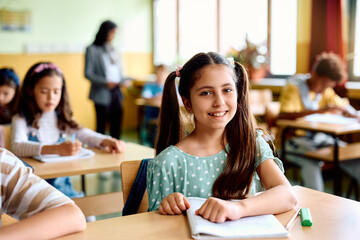 Wall Mural - Happy elementary student during class at school looking at camera.