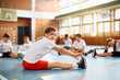 © Drazen - Smiling schoolgirl stretching her leg during physical activity class and looking at camera.