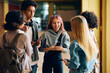 © Drazen - Cheerful high school students have fun while talking in hallway.