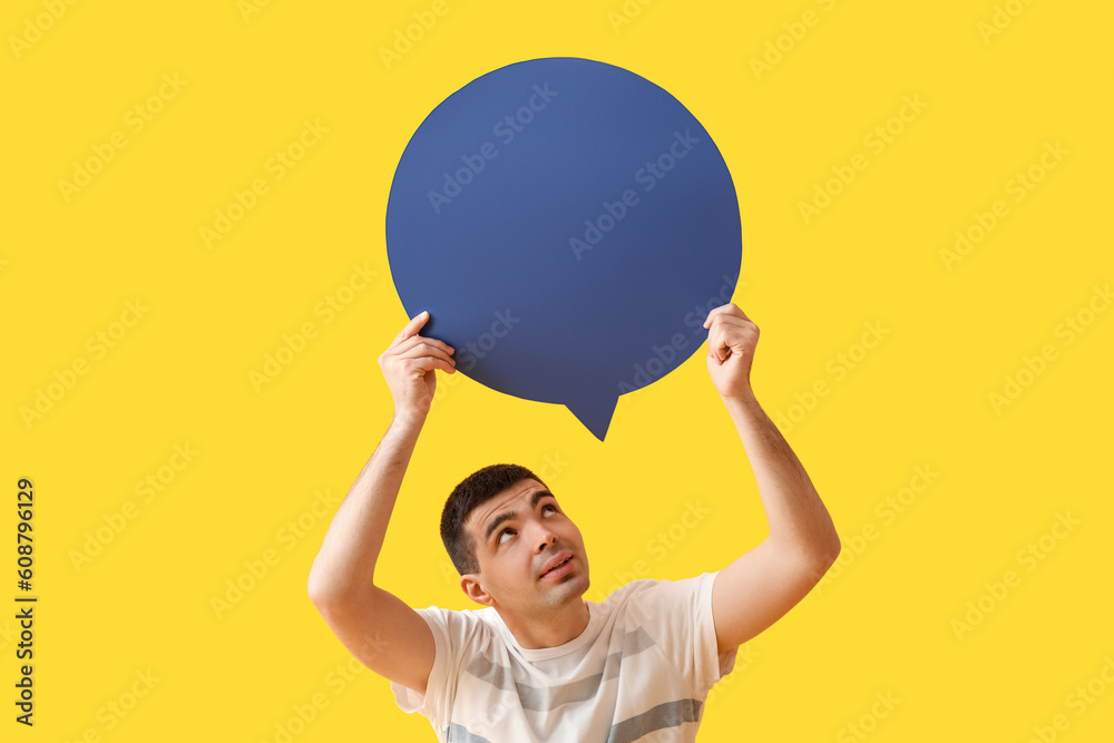 Handsome young man with blank speech bubble on yellow background