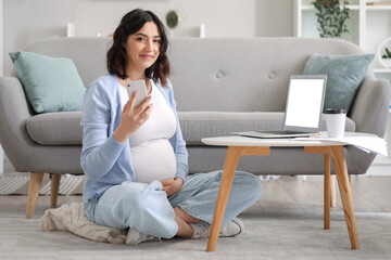 Canvas Print - Young pregnant woman working with mobile phone at home