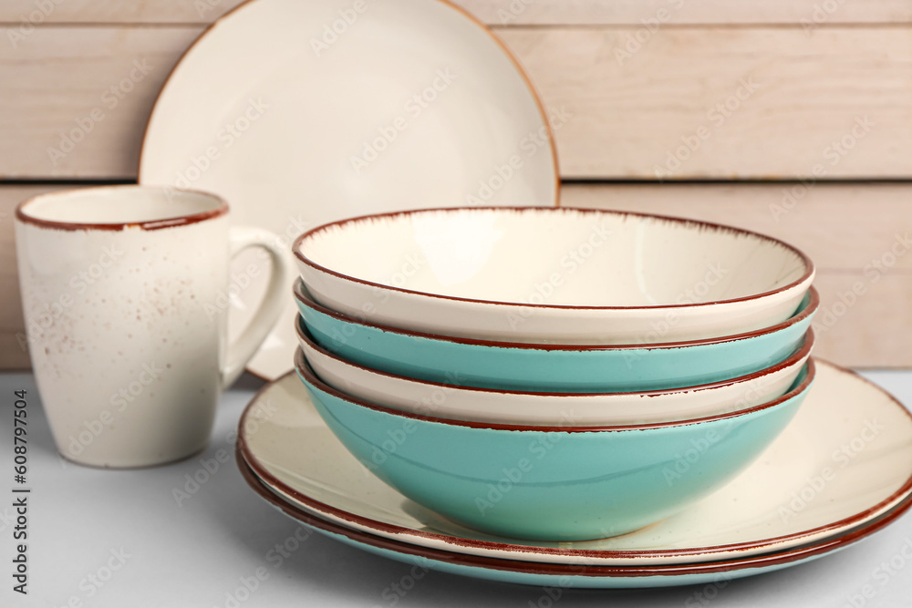 Set of different dishes on table near white wooden wall