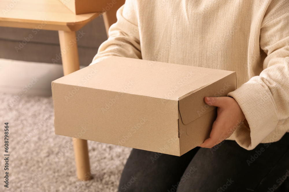 Woman holding box with shoes in room