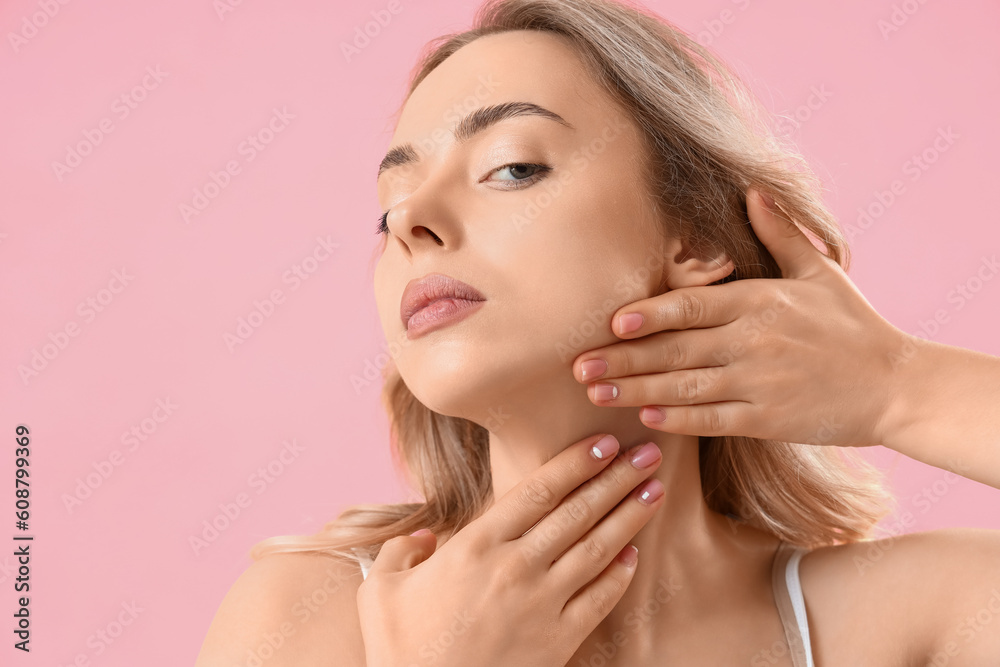 Young woman doing face building exercise on pink background, closeup
