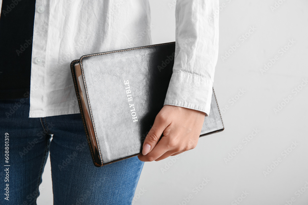 Young woman with Holy Bible on light background, closeup