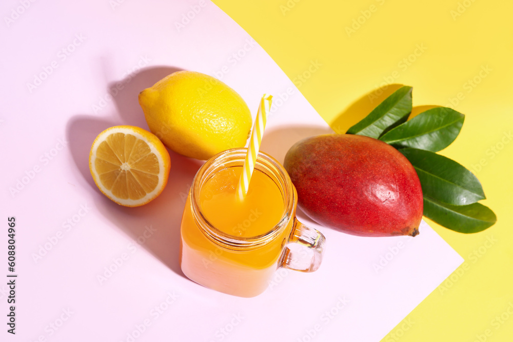 Mason jar of fresh mango smoothie and lemon on color background