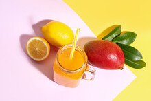 Mason Jar Of Fresh Mango Smoothie And Lemon On Color Background