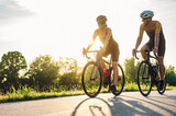 Couple riding bicycles outside of the city and wearing helmets and sunglasses