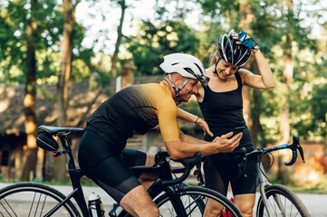 Wall Mural - Couple using smartphone while taking a break from bicycle riding