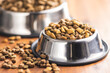 Dry kibble pet food. Dog or cat food in bowl on wooden table.