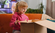 © Andrii Iemelianenko - Happy young child kid girl unpacking delivery parcel. Smiling satisfied teen toddler shopper, online shop customer opening cardboard box receiving purchase gift by fast postal shipping at home room
