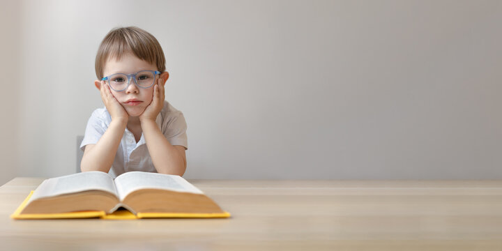Wall Mural - portrait of a smart little boy in glasses with an open book,  copy space