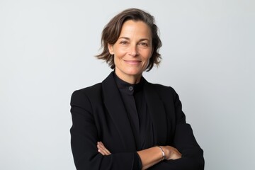 Wall Mural - Portrait of smiling mature businesswoman with arms crossed standing against white background