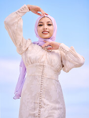 Wall Mural - Portrait, fashion or faith with a happy muslim woman on a blue sky background in a scarf for style. Islam, religion and hijab with a trendy young saudi person posing outside in contemporary clothes