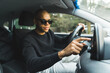 © PoppyPix - Handsome young black guy using a GPS navigation system touch screen in the car. High quality photo