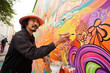 © Michael Schauer - Hispanic middle aged man painting a mural on wall