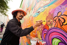 Hispanic Middle Aged Man Painting A Mural On Wall