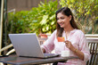 © PRASANNAPIX - Happy Indian woman using laptop and showing bank card. Digital payment concept.