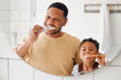 © K.A./peopleimages.com - Brushing teeth, father and child in a home bathroom for dental health and wellness with smile. Face of a man and african boy kid learning to clean mouth with a toothbrush and mirror for oral hygiene